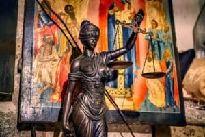 A blindfolded statue representing justice holding scales, set against an ornate background in Jerusalem.